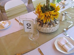 Round glass bowl, pebble stones, table number, white napkins, white table cloths and chair covers, apple green organza runner