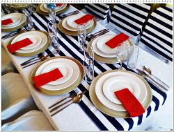 Silver baseplates, red napkins, white crockery, cutlery, glassware