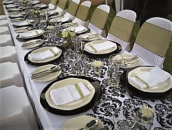 Damask patterned runner, white napkins, black baseplates, tiny glass holders for flowers, chaircovers, tiebacks, crockery, cutlery